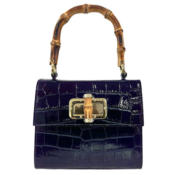 The JMNARTE Coco Pattern Handbag displaying a rigid structural leather handbag silhouette beautifully contrasted with a natural organic bamboo top handle.